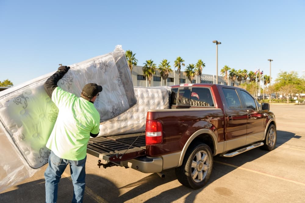A volunteer with the nonprofit helps transport a mattress to a family in need. (Courtesy Houston Children's Charity)