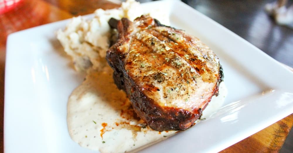 Double Cut Smoked Pork Chop ($24): A wood fire-roasted pork chop is paired with creole mustard and mashed potatoes. (Emily Lincke/Community Impact Newspaper)