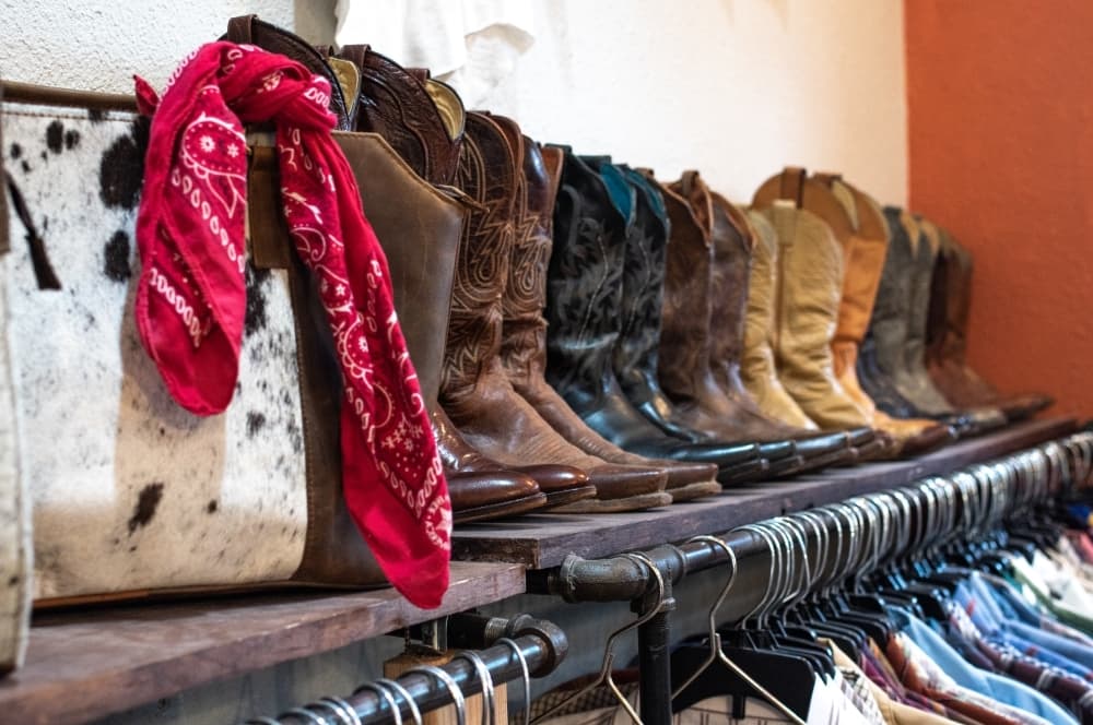 
Cowhide bags and multiple racks of cowboy boots are for sale at Guadalupe Vintage & Co.
