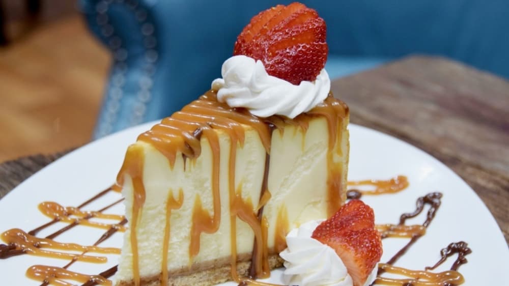 This classic cheesecake is topped with caramel sauce, chocolate sauce and berries. (Amber Friend/Community Impact Newspaper)