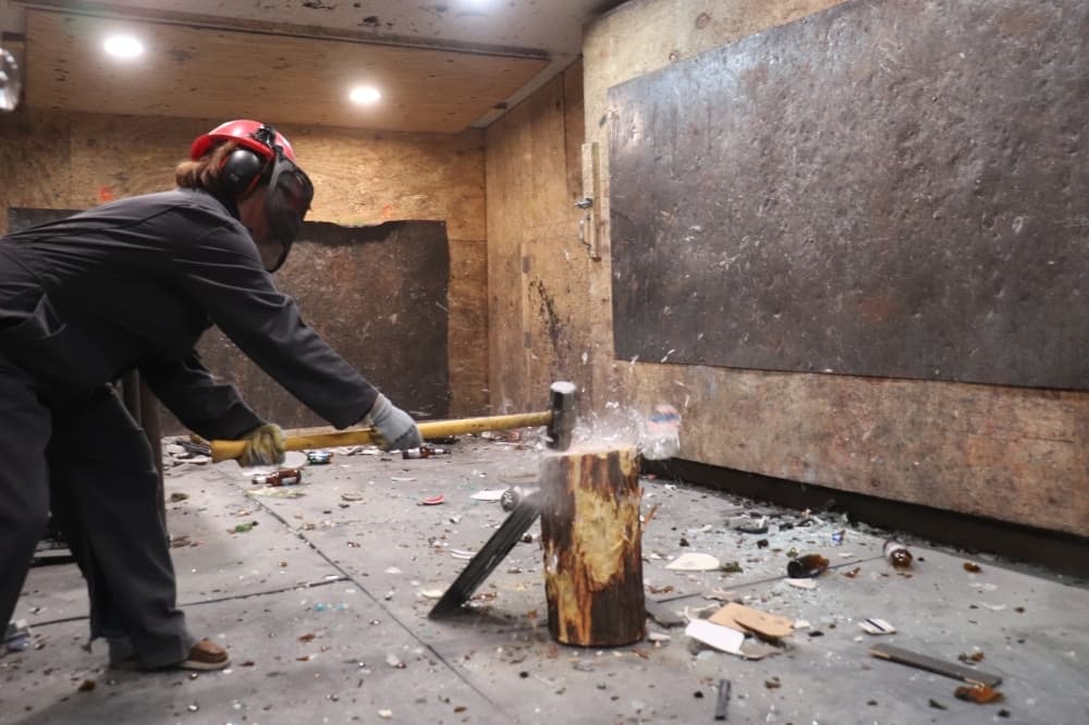 A patron smashes glassware in the rage room. (Zara Flores/Community Impact Newspaper)