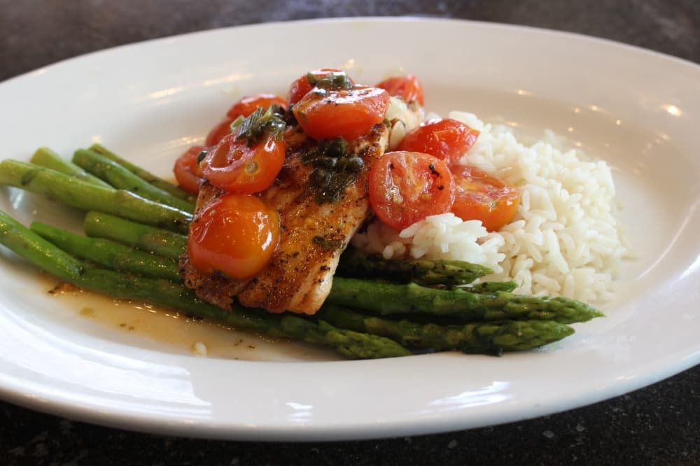 Garlic caper grilled salmon ($19.49) is a favorite entree dish. It is salmon served with cherry tomatoes, lemon, white wine and a choice of two sides. (Jackson King/Community Impact Newspaper)