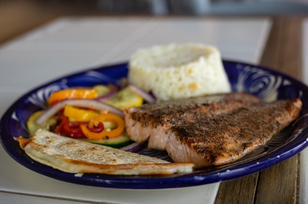 The grilled salmon is served with two sides and a cheese quesadilla.