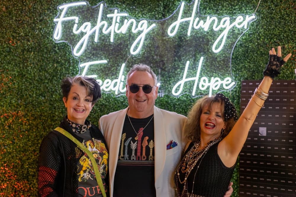 Debra Staley, left, and Gil Staley, CEO of The Woodlands Economic Development Partnership, are joined by an attendee in a Madonna costume at the rock-themed gala. (Courtesy Montgomery County Food Bank)