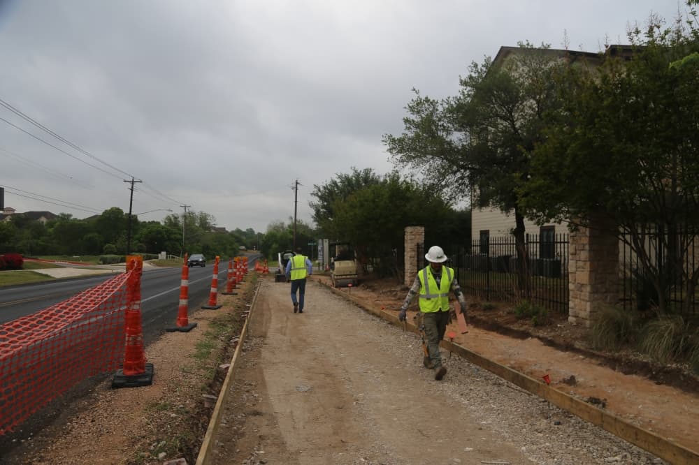 Workers prepare the sidewalk area.