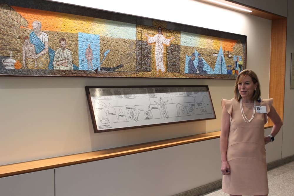 CEO Debra Sukin explained a mosaic piece on display at the hospital. (Andrew Christman/Community Impact Newspaper)