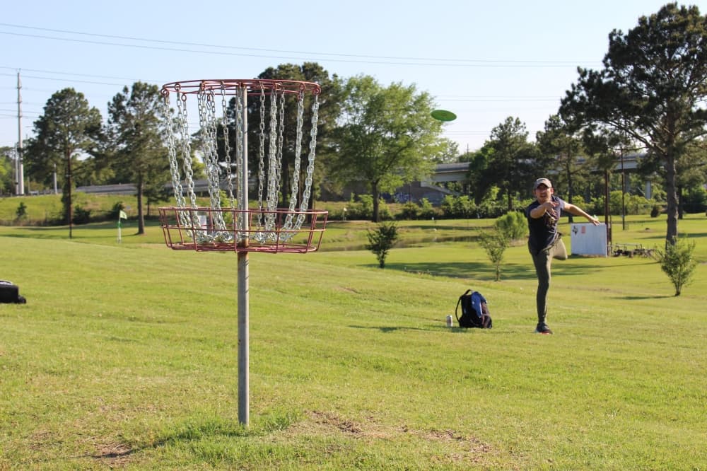 Nick Bustamento practices his putting on Humble SportsPlex’s 18-hole disc golf course. (Wesley Gardner/Community Impact Newspaper)
