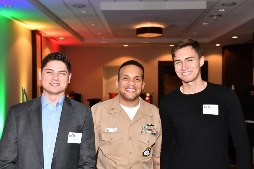 three people standing together with rainbow lights behind them
