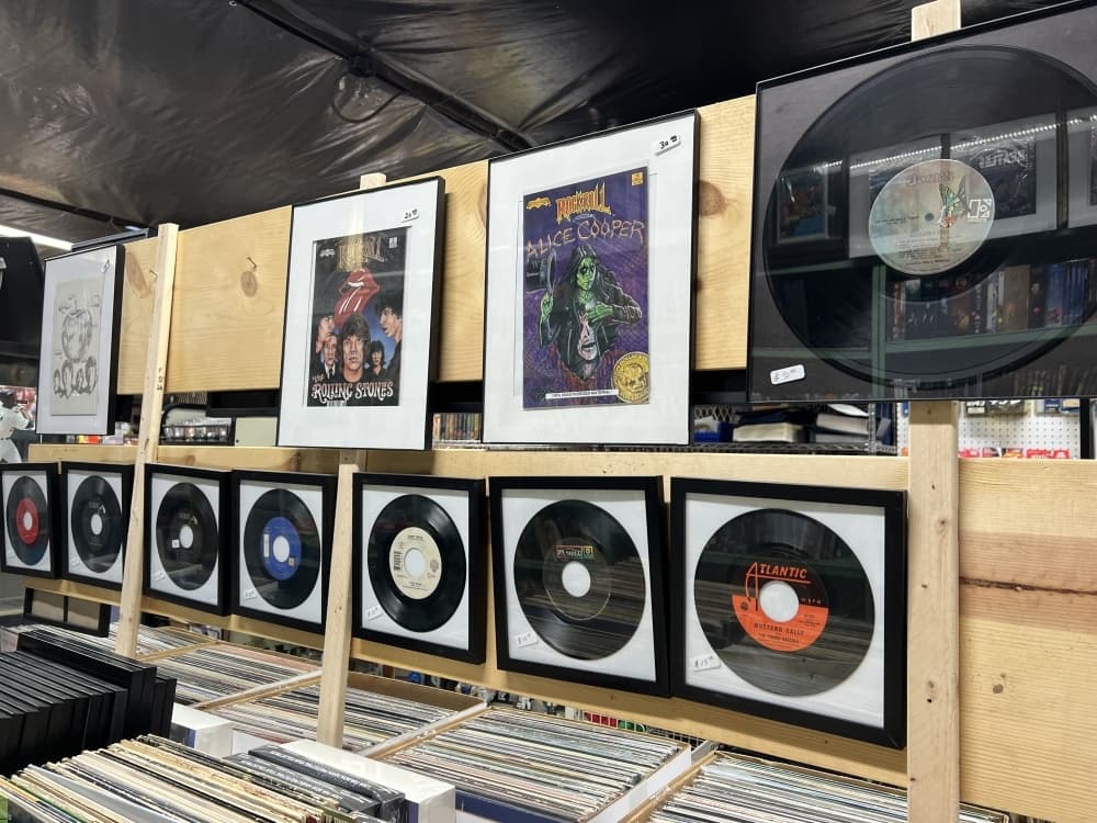 An indoor vendor sells a variety of framed music memorabilia.