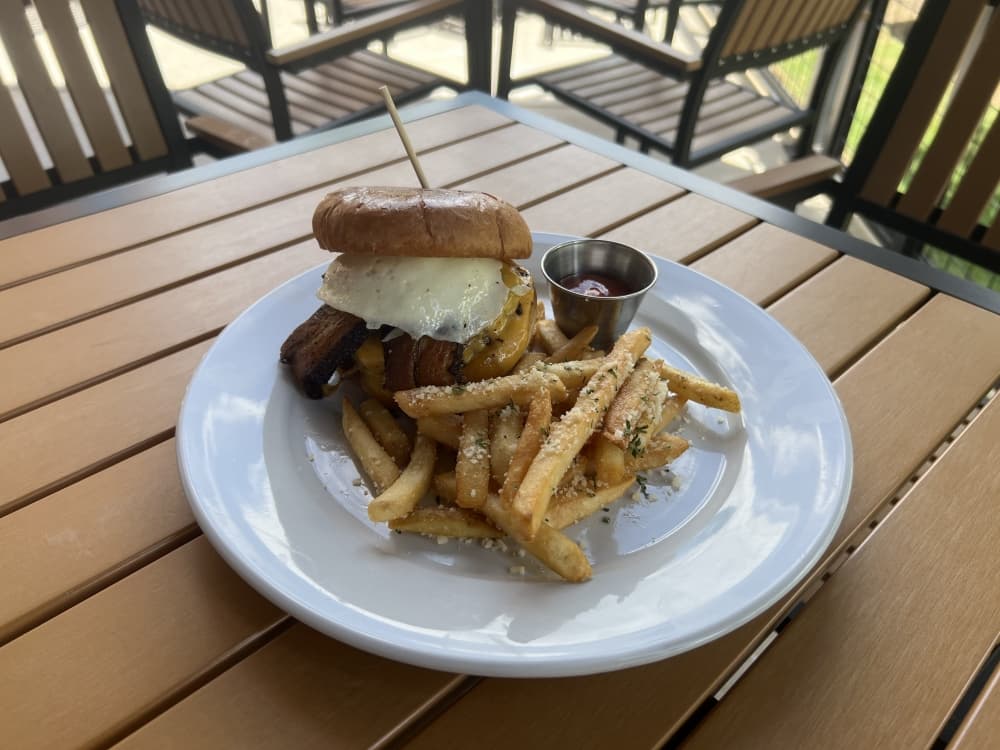 A half-pound Angus beef patty, cheddar cheese, house-smoked pork belly and a fried egg are placed on a brioche bun in the Pre-Party Burger ($16). (Maegan Kirby/Community Impact Newspaper)