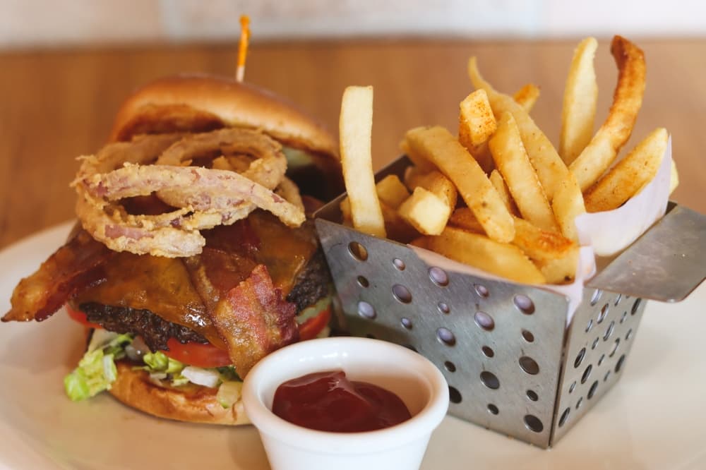 The Texas burger ($13.95) is one of the most popular items on the menu, according to the Tuney family. The charbroiled burger is topped with cheddar cheese, crispy bacon, fried onion strings, lettuce, tomato, pickles and barbecue sauce on a brioche bun and is served with french fries. (Grant Johnson/Community Impact Newspaper)