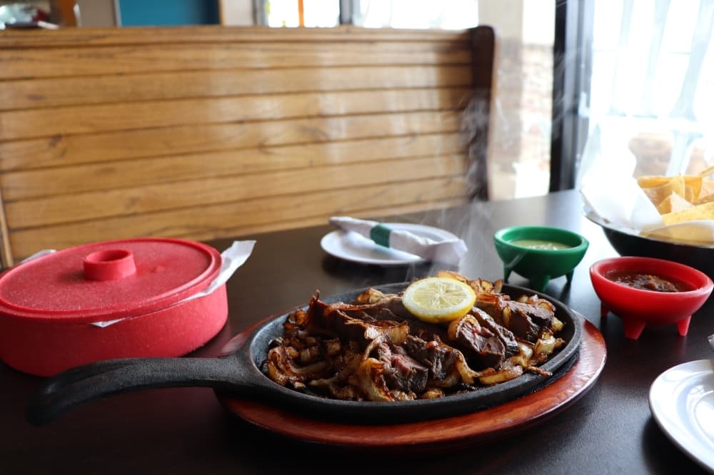 Beef fajitas are served with rice, green sauce, guacamole and flour tortillas. (Cynthia Zelaya/Community Impact)
