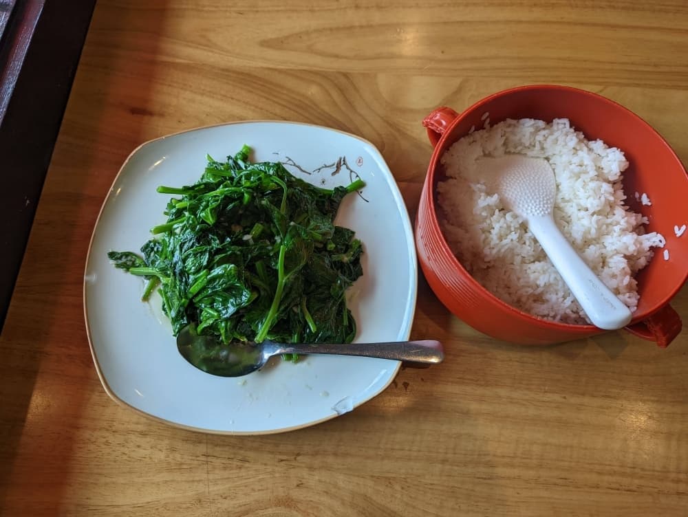 Stir fried pea shoots with garlic ($17): Pea shoots and garlic are served alongside a bed of white rice. (George Wiebe/Community Impact Newspaper)