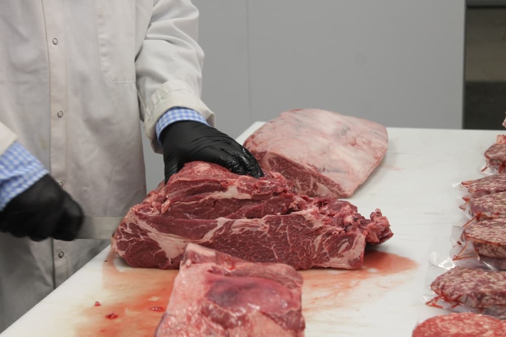 Alec Ramirez breaks down beef in the Royalty Meat Co.'s cold room. (Renee Farmer/Community Impact Newspaper)