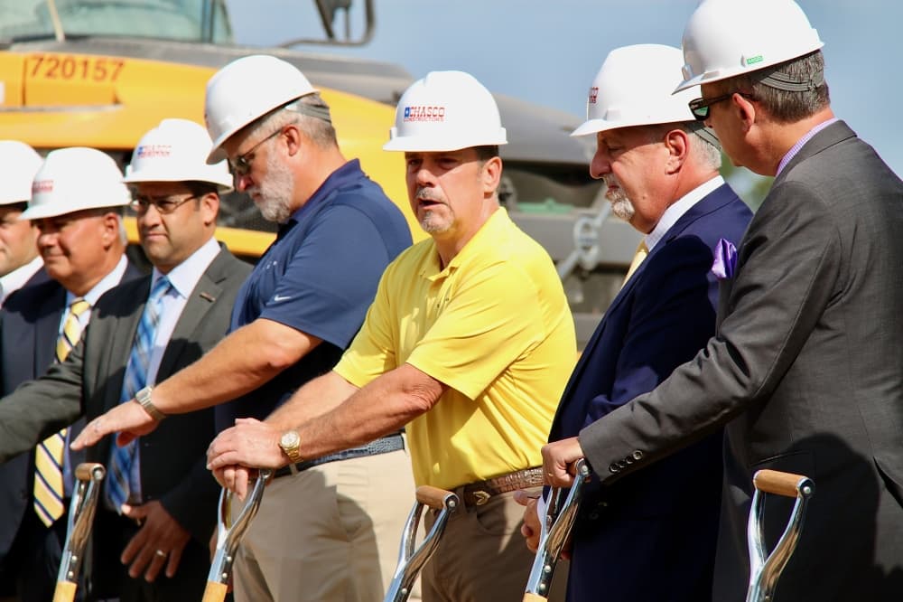 Man in yellow shirt and other men holding shovels