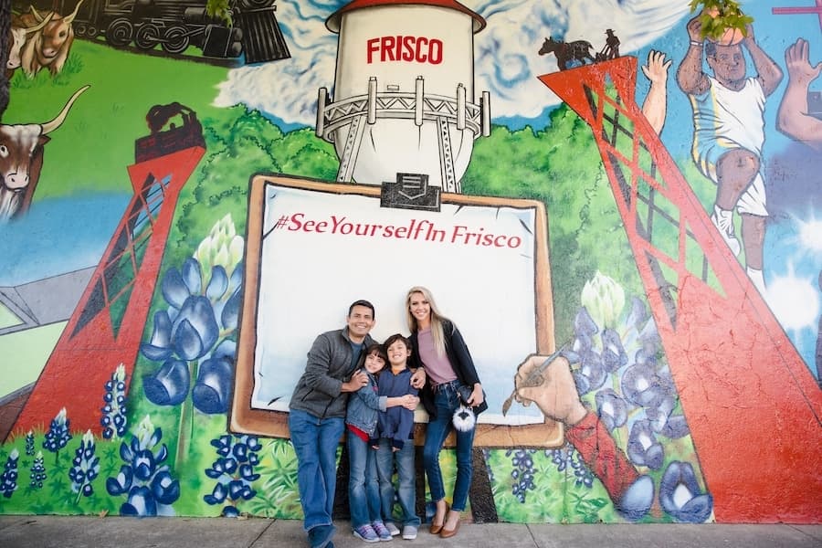 family standing against mural wall in Frisco