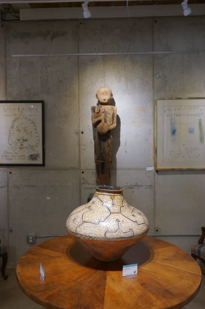 A Peruvian Shipido-Conibo Pottery Vessel from the 20th Century is available to purchase for $2,500 at the Lark Mason Gallery. Behind the pottery vessel is a New Guinea Carved Wood Standing Figure on retail for $1,125. On either side of the pottery vessel are two Sala Gaspar Exhibition Posters by Pablo Picasso from 1968 and 1961. (Sierra Martin/Community Impact Newspaper)