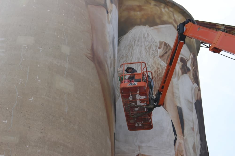 Artist Guido van Helten works on the McKinney Silo Mural Project on Aug. 15. (Colby Farr/Community Impact Newspaper)