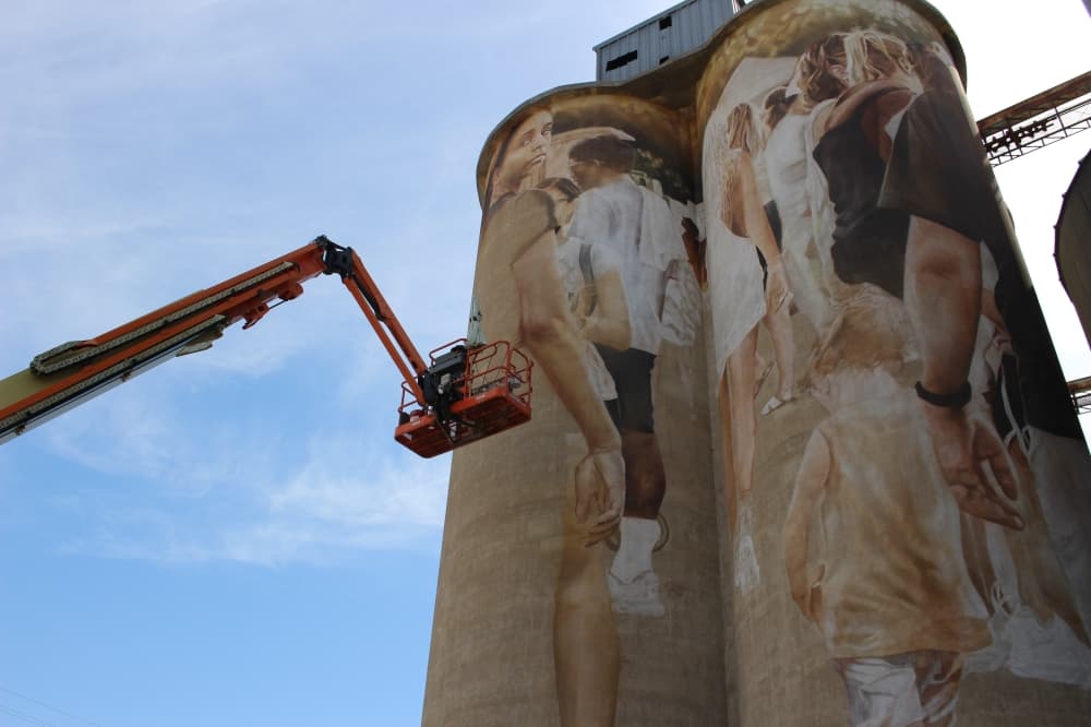 Artist Guido van Helten works on the McKinney Silo Mural Project on Aug. 15. (Colby Farr/Community Impact Newspaper)