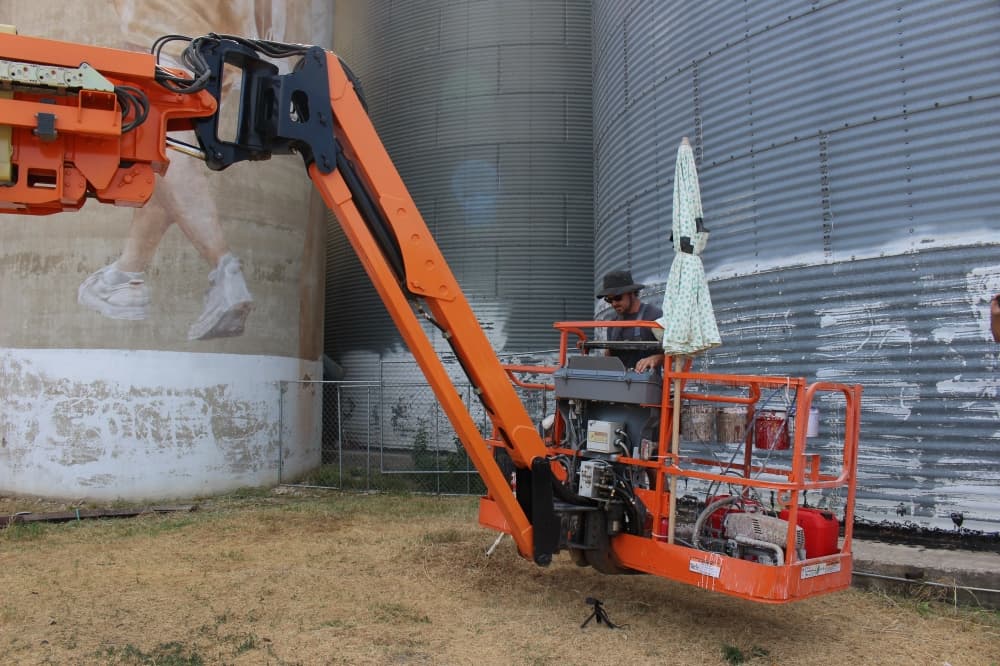 Artist Guido van Helten works on the McKinney Silo Mural Project on Aug. 15. (Colby Farr/Community Impact Newspaper)