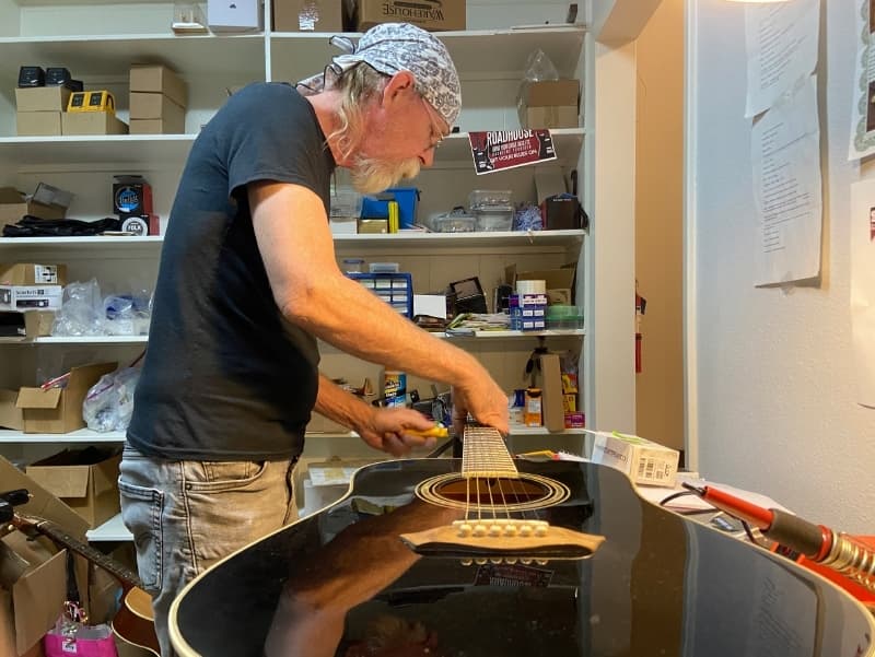 Pepper sets up an acoustic steel string guitar on his workbench. 