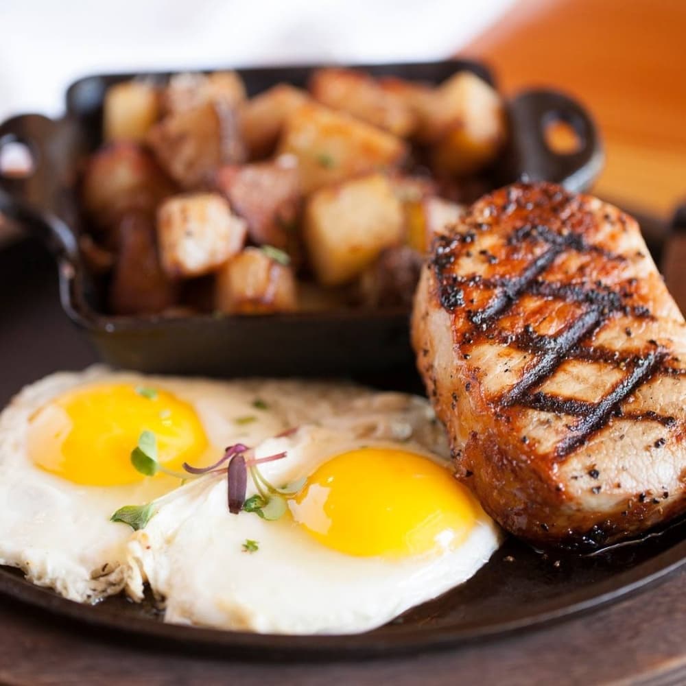 Grilled Pork Chop & Eggs from Krause's Cafe is two eggs, a choice of home fries, hash browns, grits, or black beans and a biscuit. $12 (Krause's Cafe/Community Impact Newspaper)