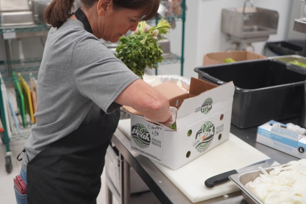 Volunteers examine donated food supplies to prepare meals for dinner. (Christopher Goodwin/Community Impact Newspaper)