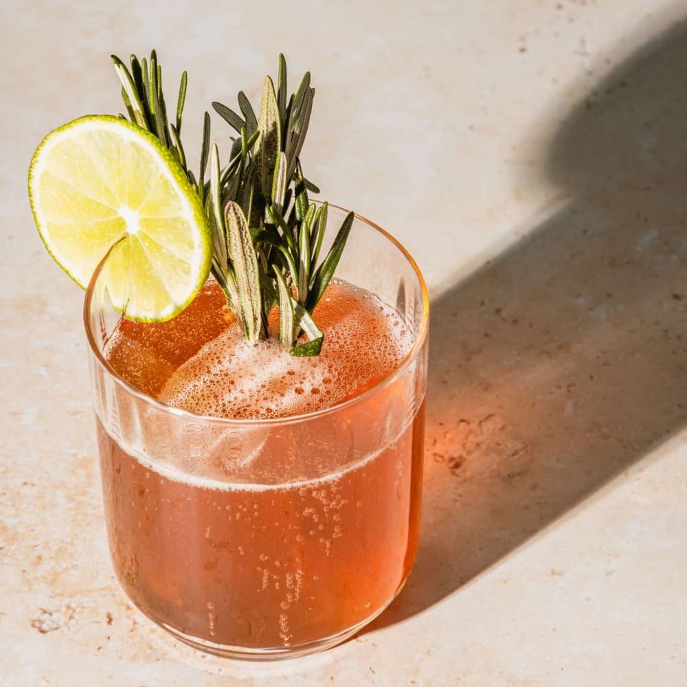 cocktail with lime wedge and rosemary