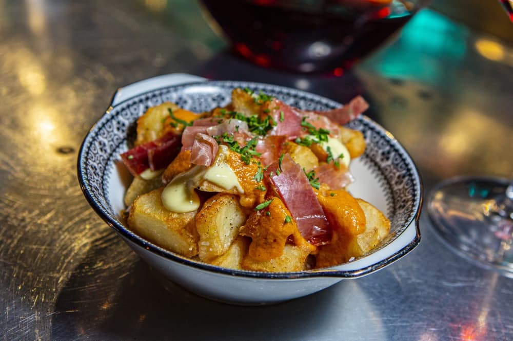Patatas Bravas ($14): Potatoes are piled high with brava sauce, garlic aioli, jamon and serrano. (Courtesy Plane & Level)