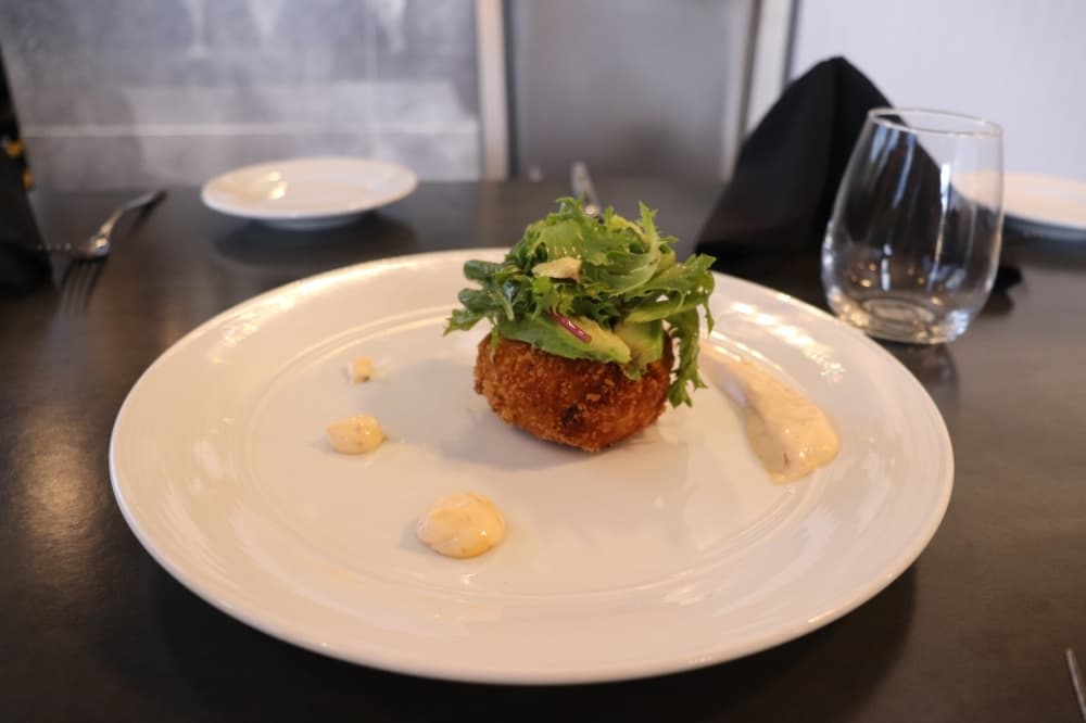 The crab cake is made from blue crab with breadcrumbs. It comes with a spicy mayonnaise sauce. 