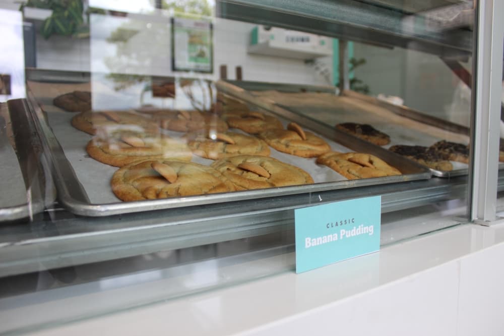 A tray of banana pudding cookies behind a glass barrier.