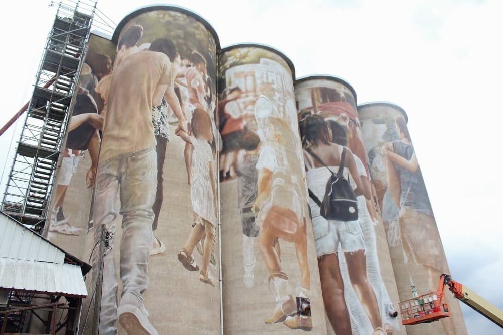 Guido van Helten paints a mural while on a mechanical lift. 