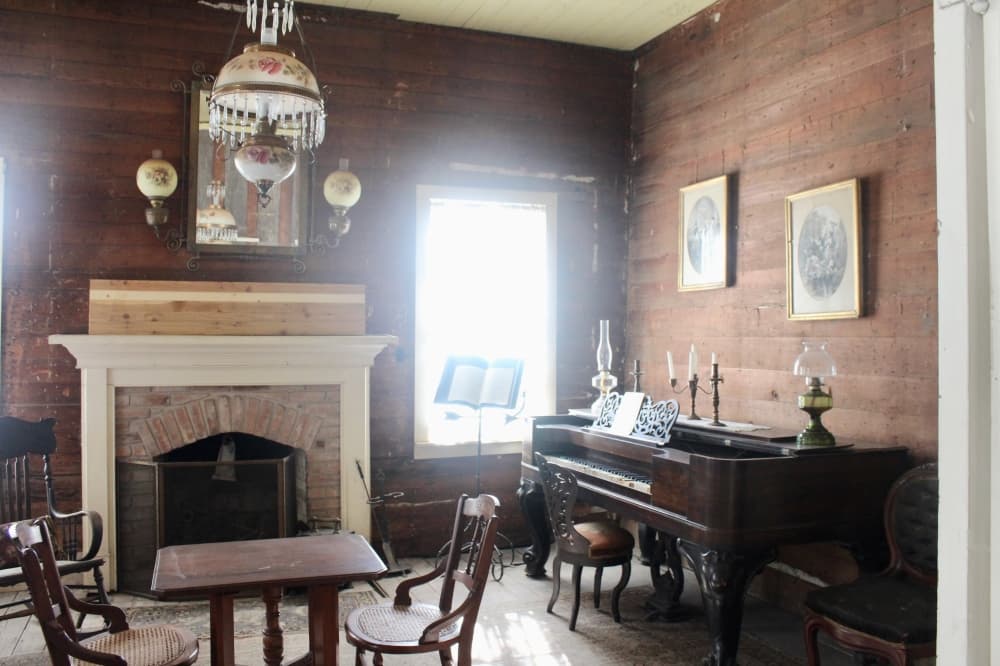 Interior of the Faires House with a dining set, desk, fireplace and chandelier. 