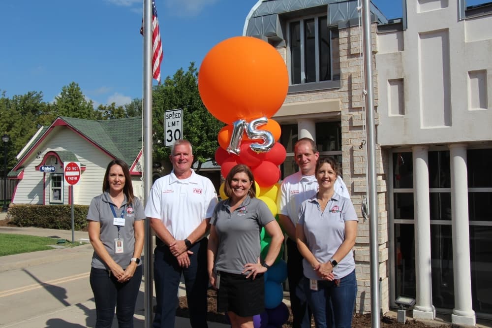 City and facility officials standing in a group in front of the 15th anniversary decorations.