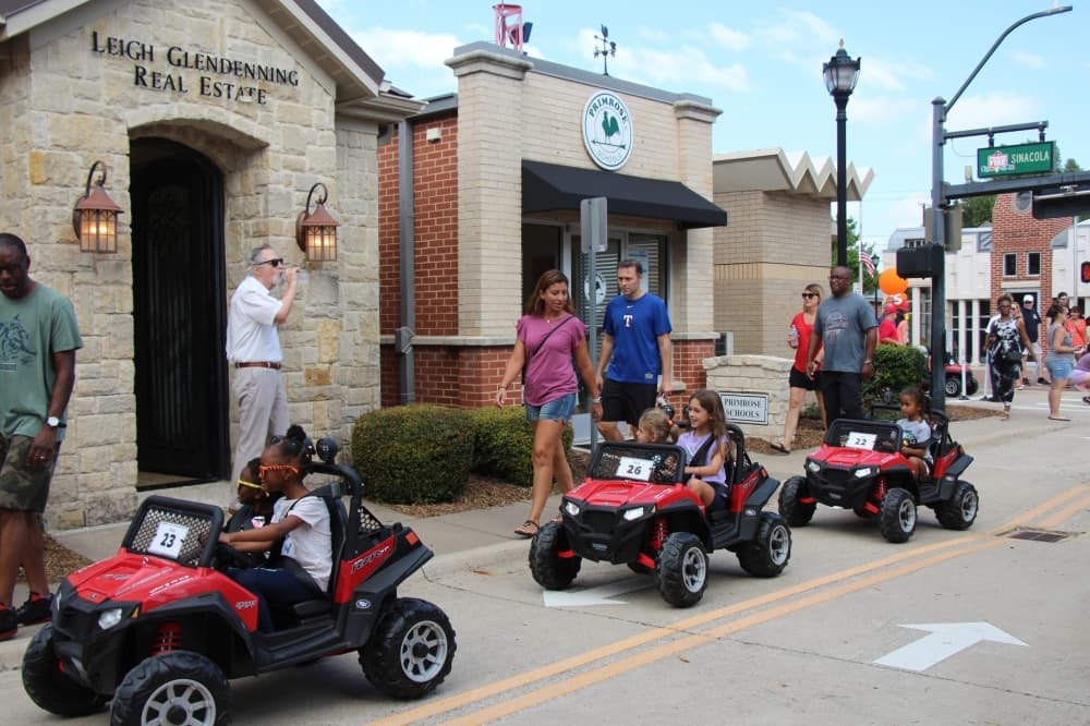Children driving in a line in power-wheels style mini Jeeps.