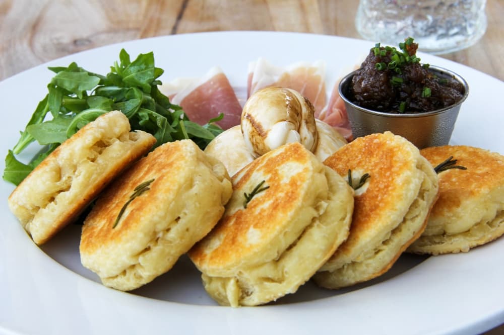 Ham and cheese plate ($18): Prosciutto, burrata, onion jam, herb salad and Italian griddle bread make up this dish. (Wesley Gardner/Community Impact)