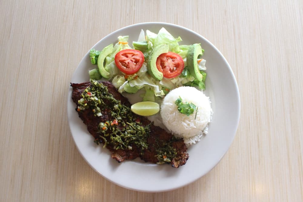 The Carne Asada Con Chimichurri ($17.99) is marinated grilled beef skirt steak with house-made Argentinian chimichurri salsa and served with rice, tortillas and avocado salad. (Lizzy Spangler/Community Impact Newspaper)