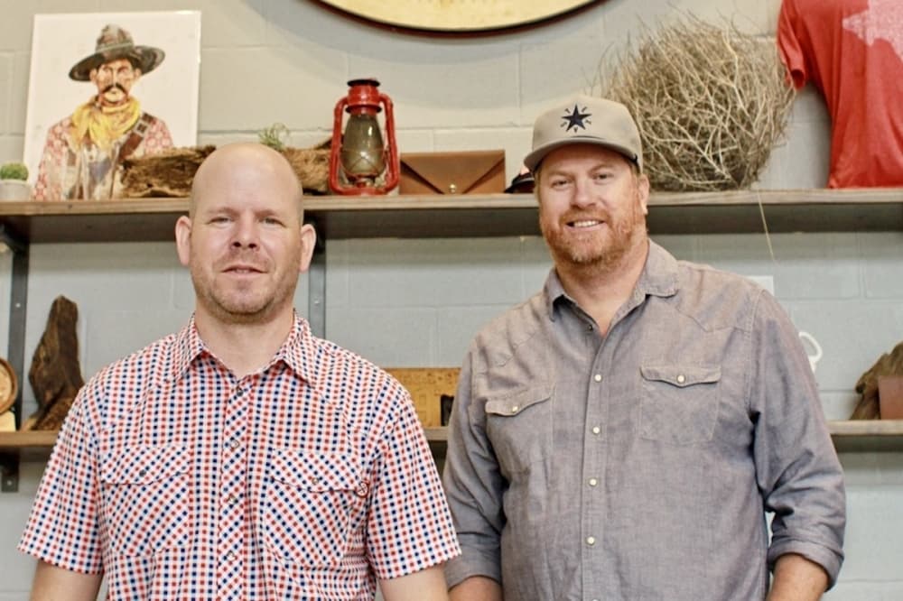 two men standing in front of shelves with decor
