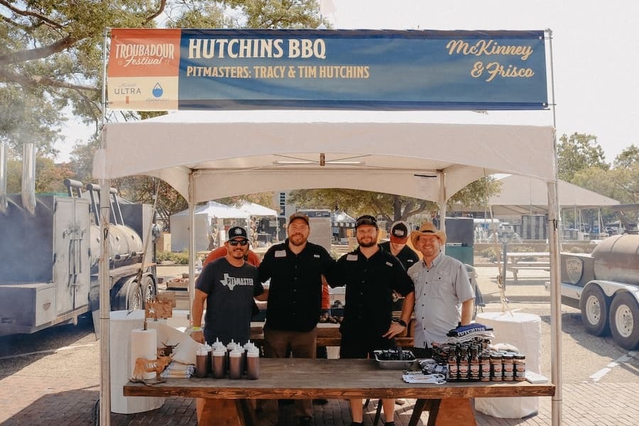 four men standing under a tent at a barbecue cookoff
