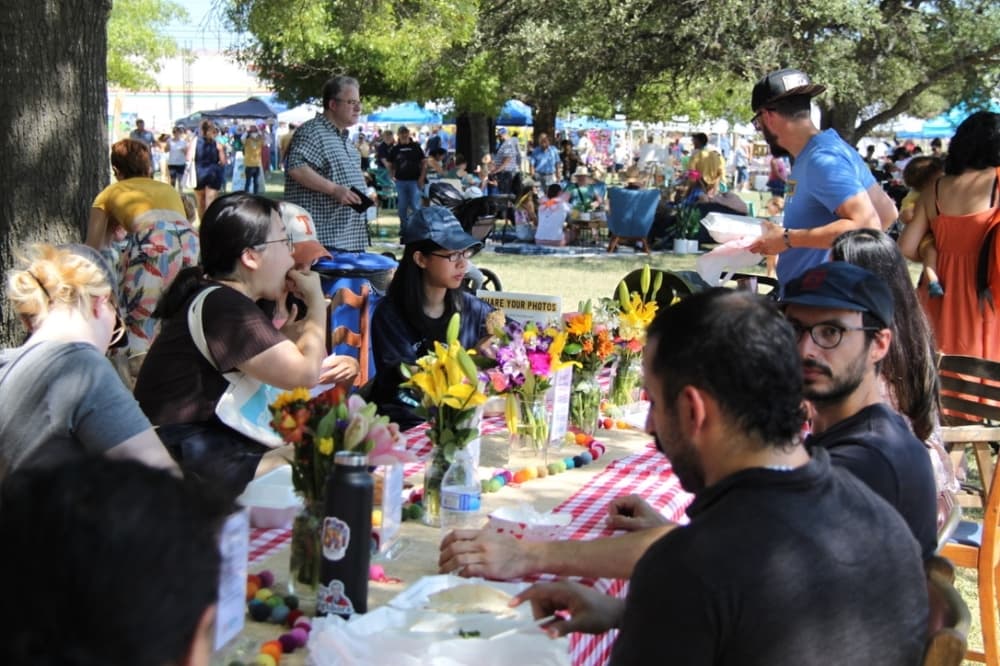 People eating in a big rectangle table at a park