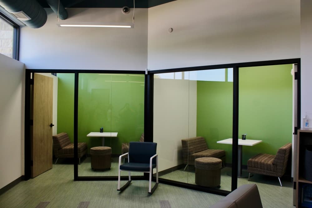 Two rooms with glass walls and a coffee table style booth.