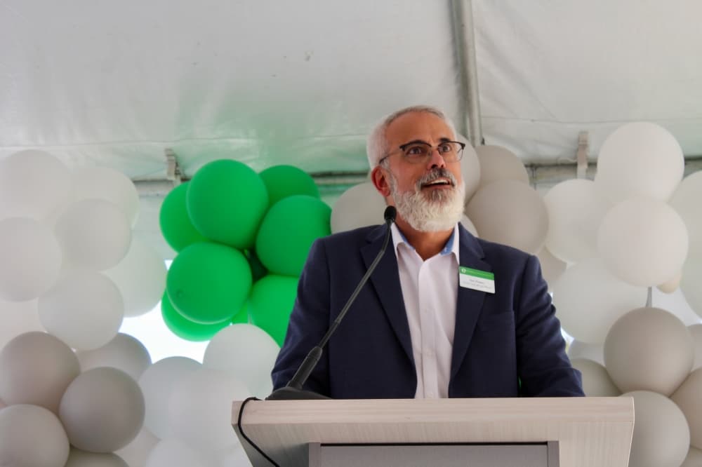 Dan Powers at a podium in front of green and white balloons.