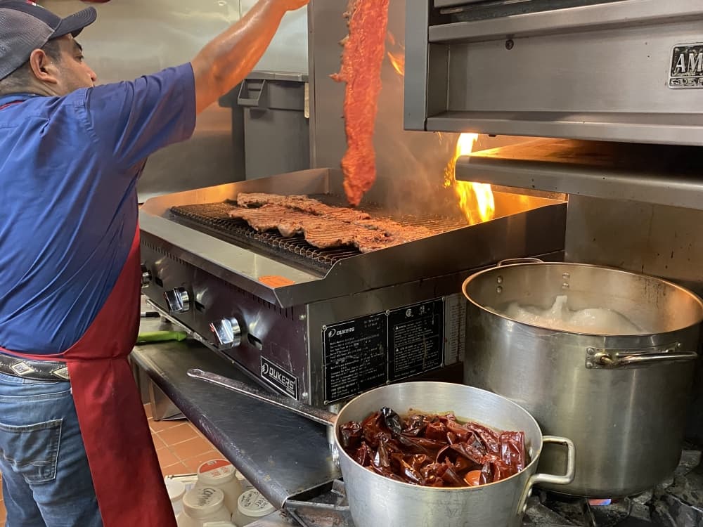 A cook flips Fajita beef on a grill. 