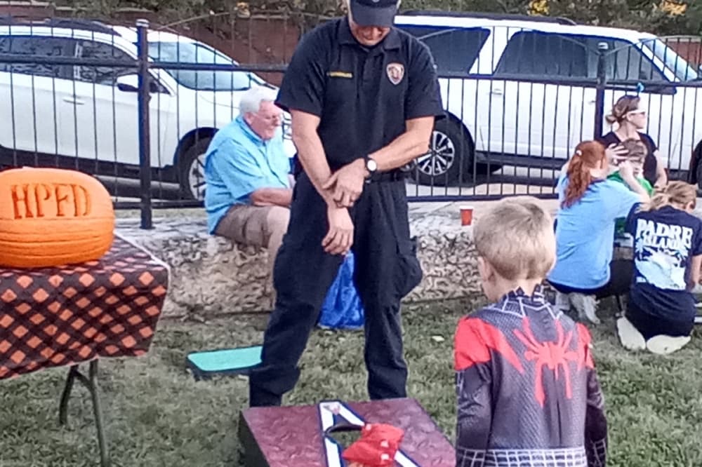 George Nungesser plays a game of cornhole as Hollywood Park firefighter Vince Gonzales watches during the Hollywood Park Community Association’s Halloween carnival held Oct. 22 at Memorial Park. (Edmond Ortiz/Community Impact)
