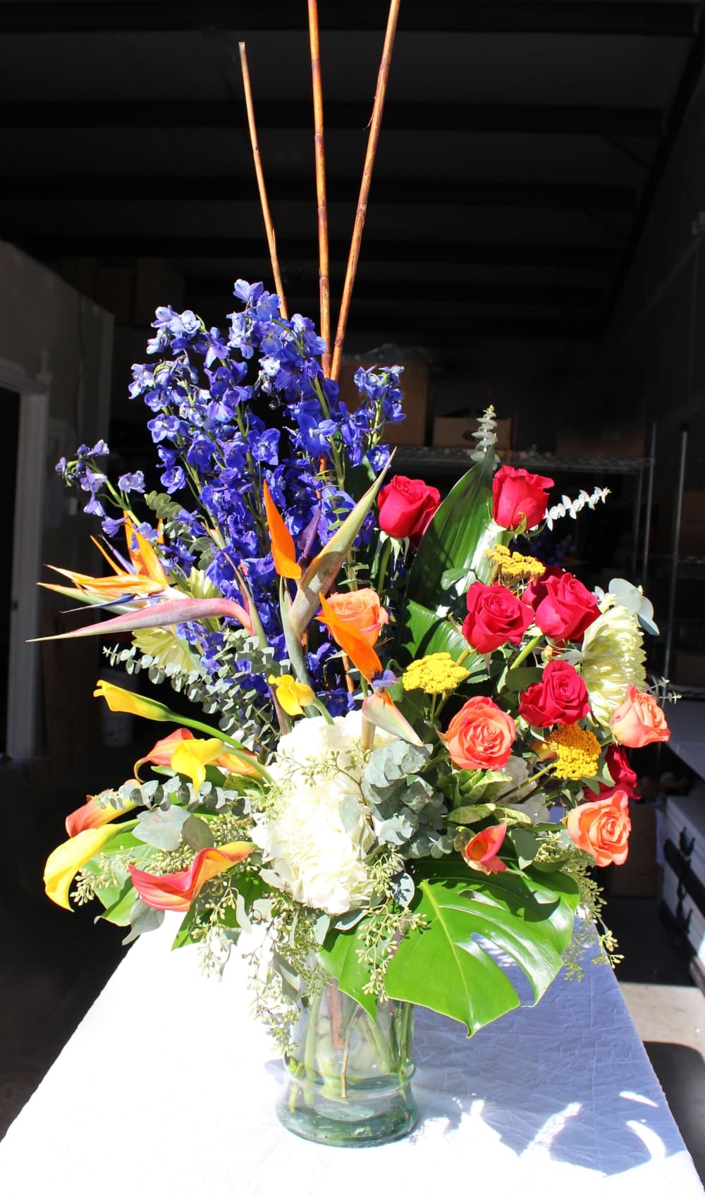 This custom arrangement features a myriad of flowers, including chrysanthemums, yellow yarrow, birds of paradise, blue delphinium and bamboo. (Karen Chaney/Community Impact)