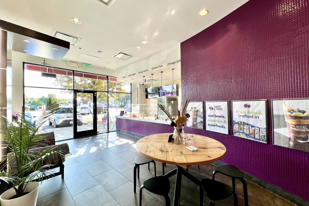 Inside of a building with a round table, chairs and a side sofa.