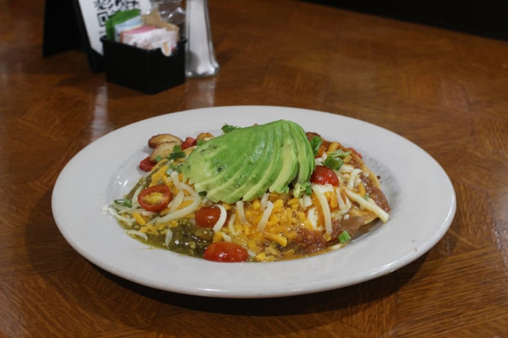 The DD Huevos Rancheros ($10.99) includes fried corn tortillas with refried beans, grape tomatoes, onions, salsa, sharp cheddar, eggs and avocado. (Kylee Haueter/Community Impact)