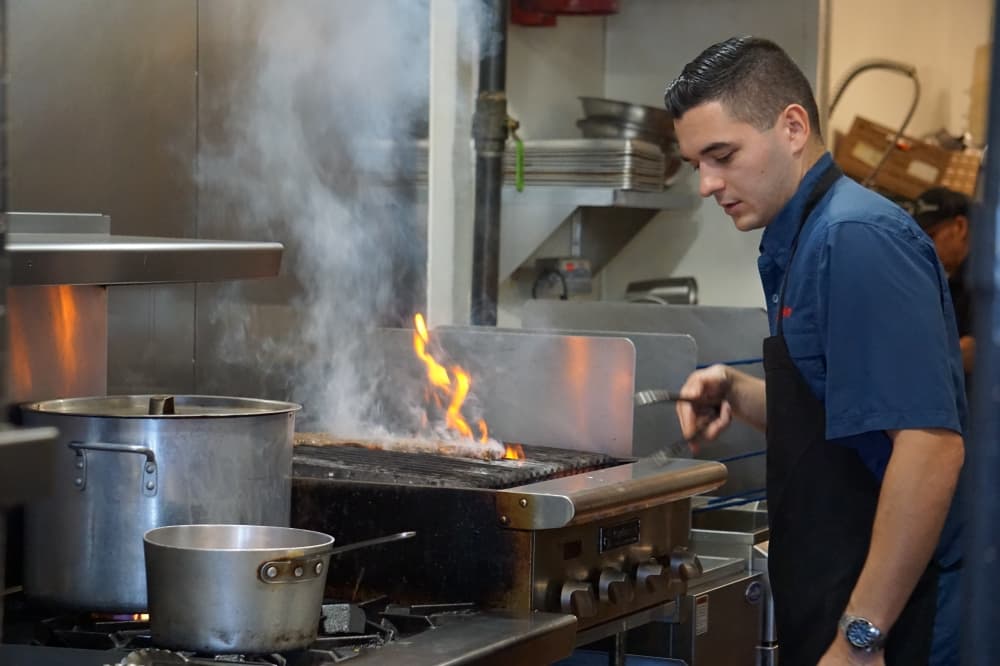 El Caribeño owner Matthew Talavera prepares churrasco, which is meat grilled over an open flame. (Mikah Boyd/Community Impact)