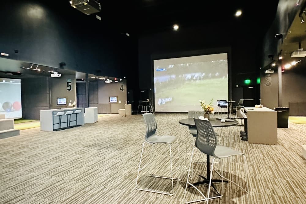Wall-sized television screen set back in a wide room.