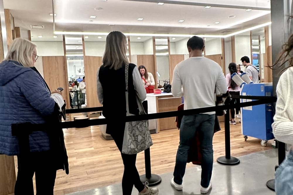People waiting in line by a dressing room in a clothing store. 